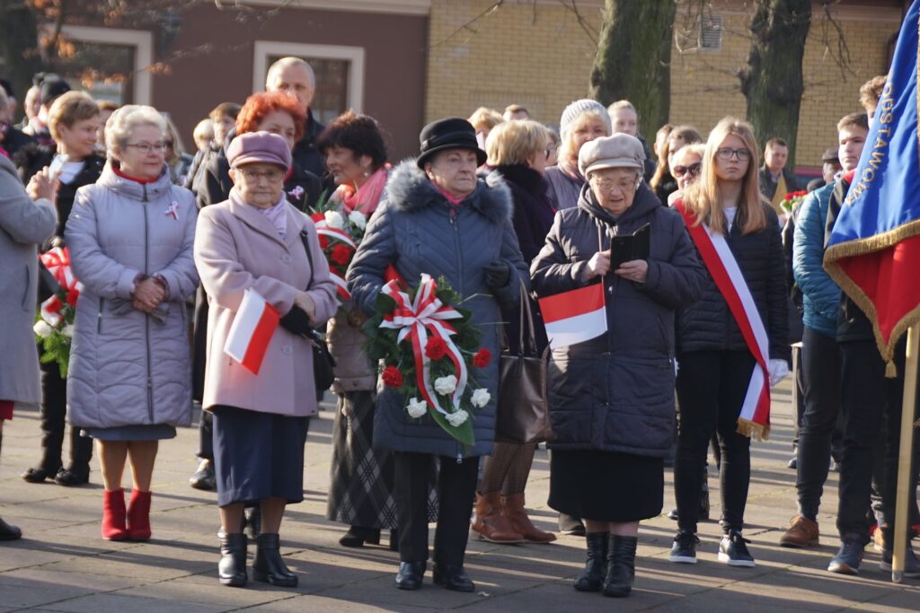 Trzy panie trzymające kwiaty w drodze do złożenia hołdu 